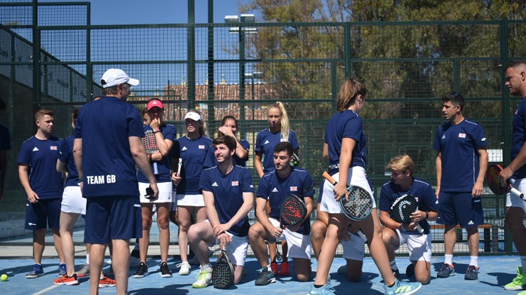 A group of padel players all knealt down on a padel court holding their rackets