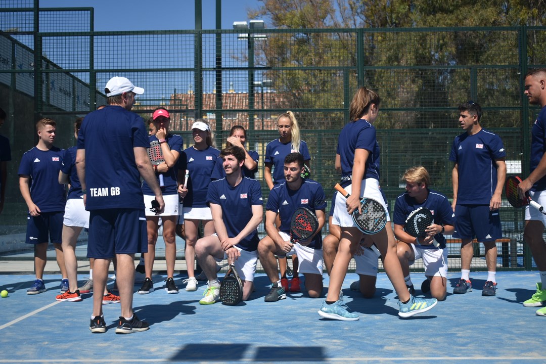 A group of padel players all knealt down on a padel court holding their rackets