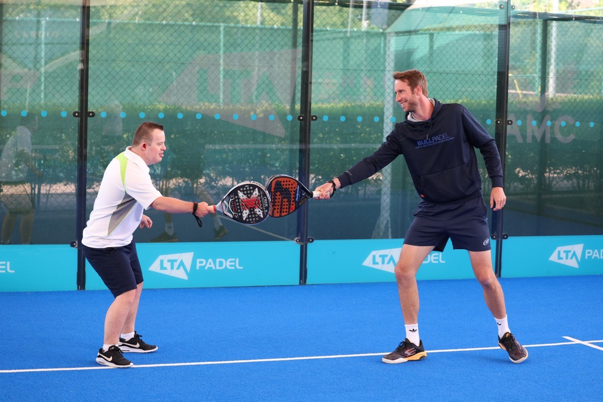 Chris Salisbury and James smiling and hitting padel rackets on the court