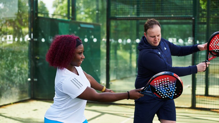 Coach teaching a women to play forehand