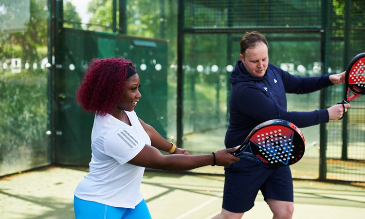 Coach teaching a women to play forehand