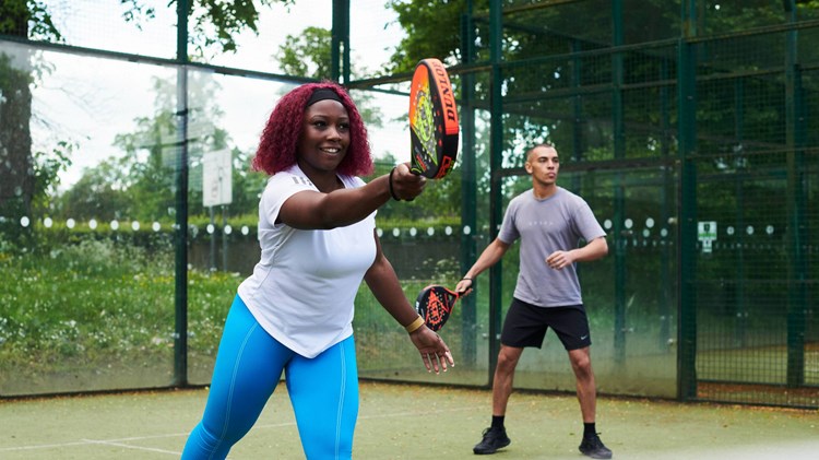 Woman on the padel court hitting a forehand in a match