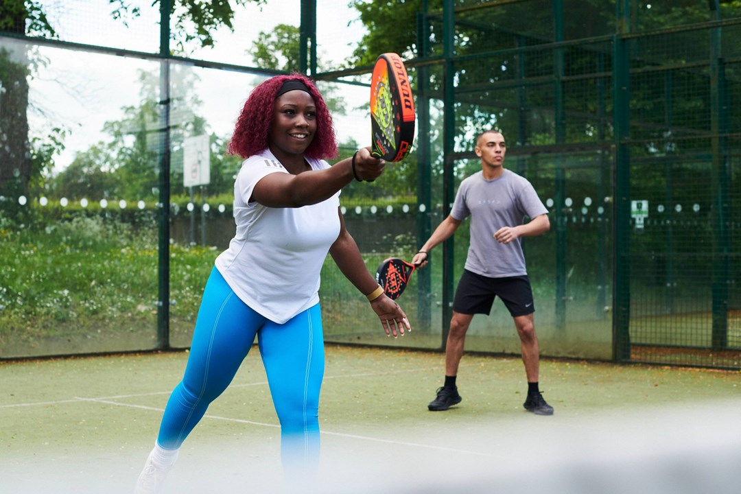 Woman on the padel court hitting a forehand in a match