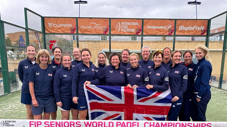 GB Senior Women's Padel team post for photo with the United Kingdom flag on a padel court