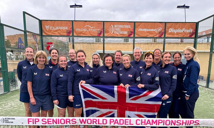 GB Senior Women's Padel team post for photo with the United Kingdom flag on a padel court