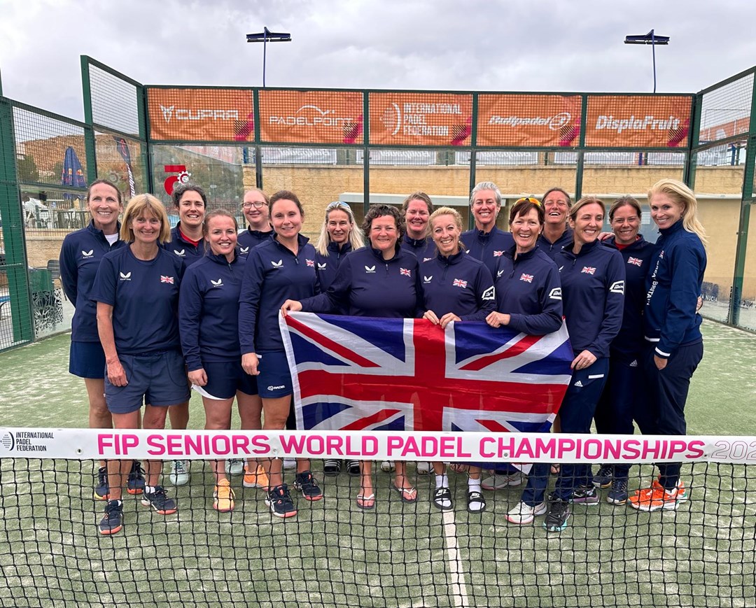 GB Senior Women's Padel team post for photo with the United Kingdom flag on a padel court