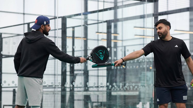 A padel doubles partnership touching rackets in between points