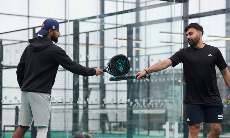 A padel doubles partnership touching rackets in between points