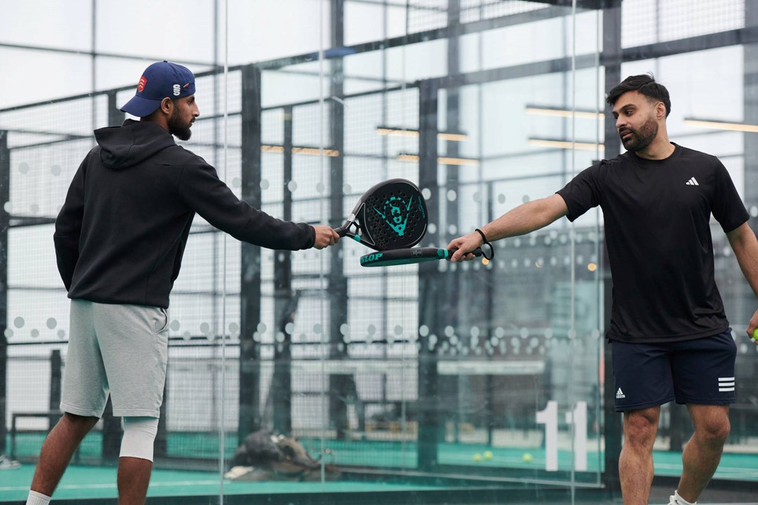 A padel doubles partnership touching rackets in between points