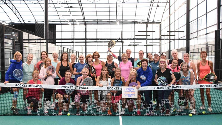 The attendees of the 2024 Female Padel Participation Day posing behind a padel net