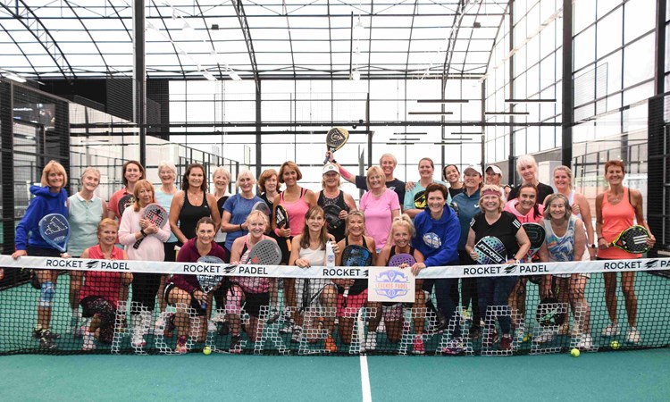 The attendees of the 2024 Female Padel Participation Day posing behind a padel net