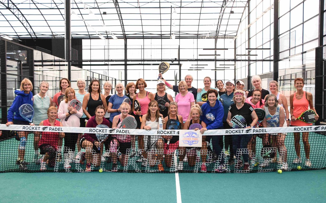 The attendees of the 2024 Female Padel Participation Day posing behind a padel net