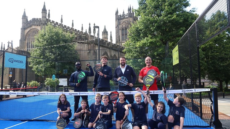A group of young children and comedian and tv presenter Jason Manford holding padel rackets on a padel court in Manchester city centren Manford  