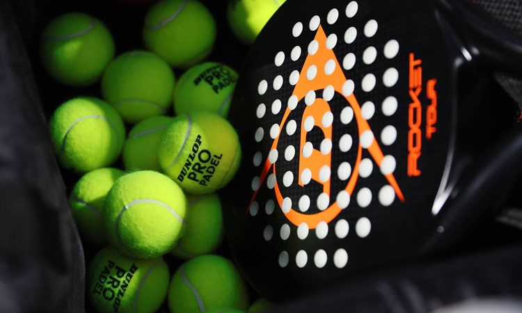 A padel racket and balls lying in a basket