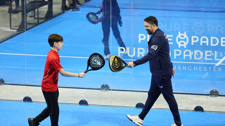 Jason Manford on the padel court with a junior player smiling and tapping rackets