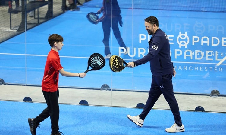 Jason Manford on the padel court with a junior player smiling and tapping rackets