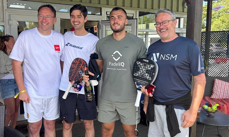 Louie Harris and Rafael Vega holding their padel bats, a bottle of champagne and their trophies alongside two men at the Padel British Tour event in Guernsey