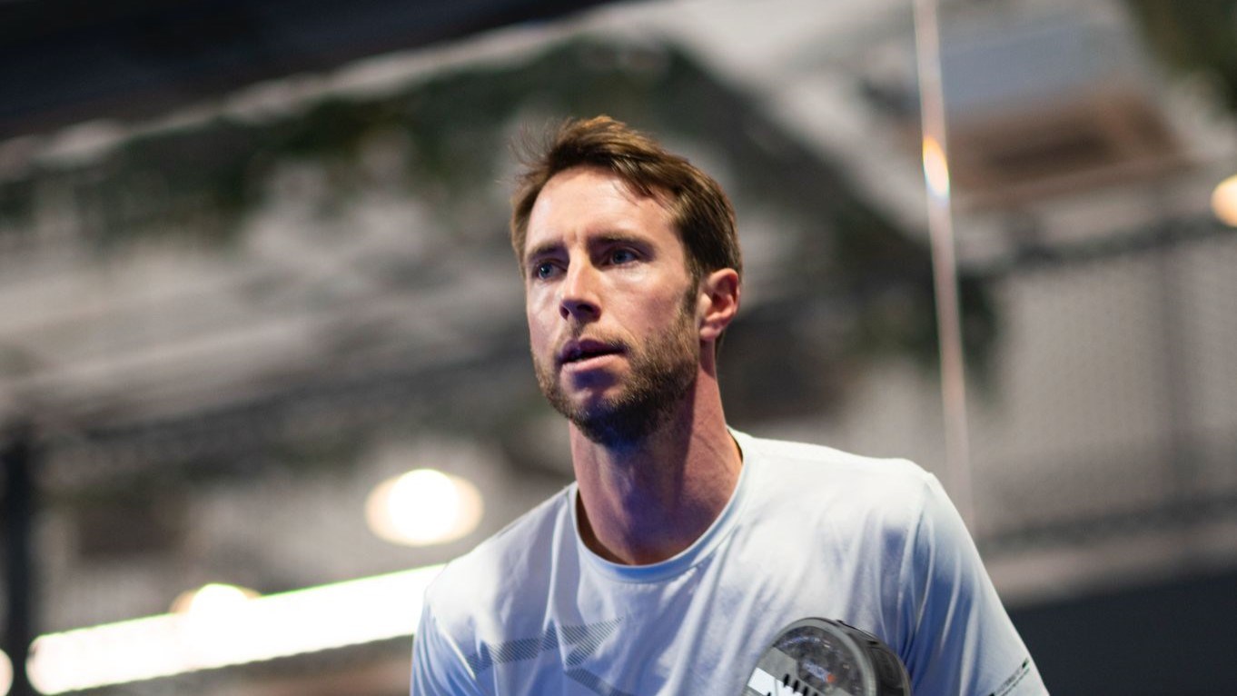 Chris Salisbury holding a padel racket and looking straight ahead on a padel court