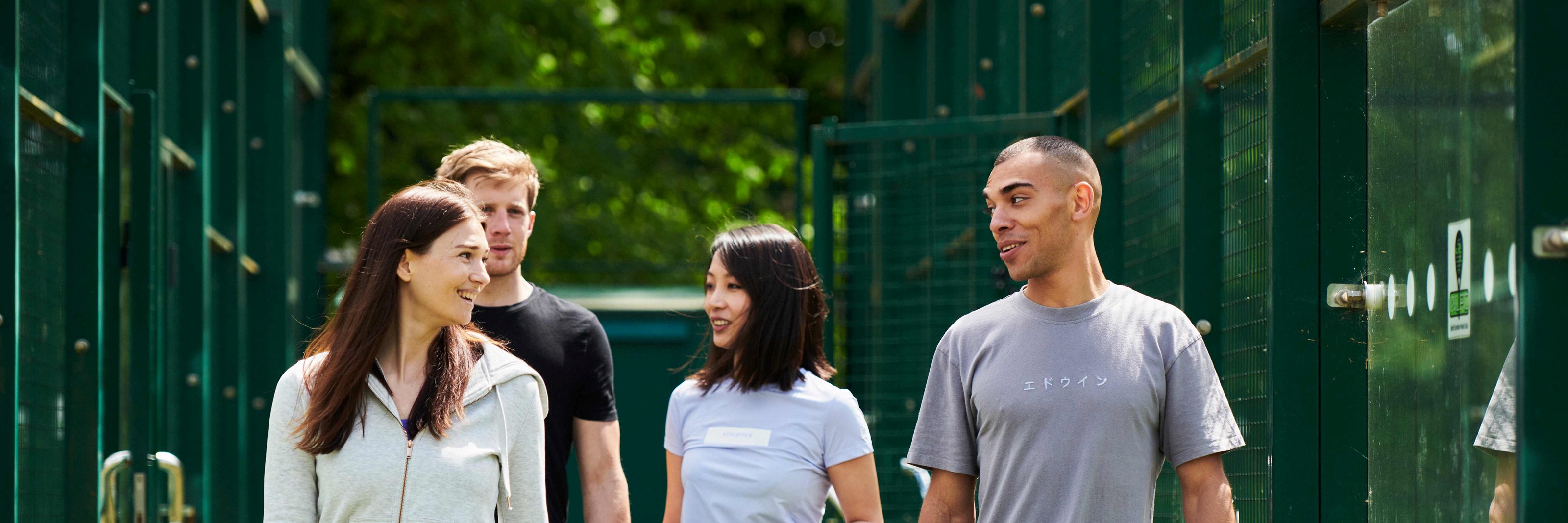 A group of four people walking to a padel court with their rackets in hand