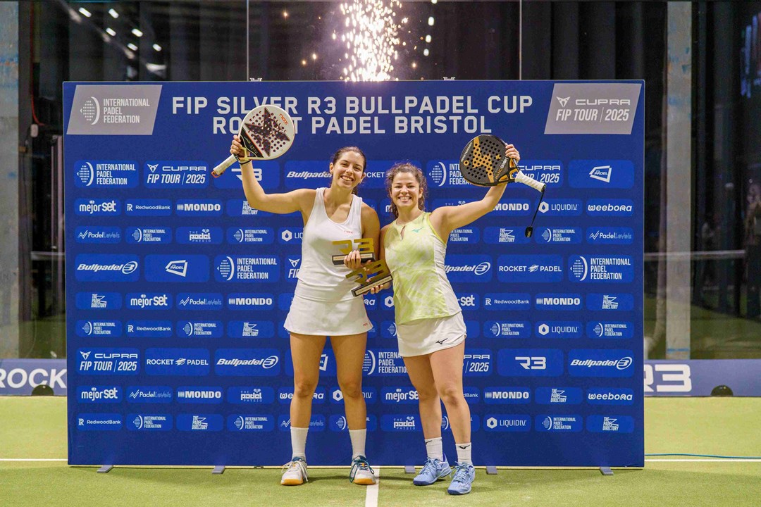 Spanish padel stars Monica Gomez Rivas and Camila Fassio Goyenche holding their padel rackets and trophies in the air after winning the FIP Silver Bristol