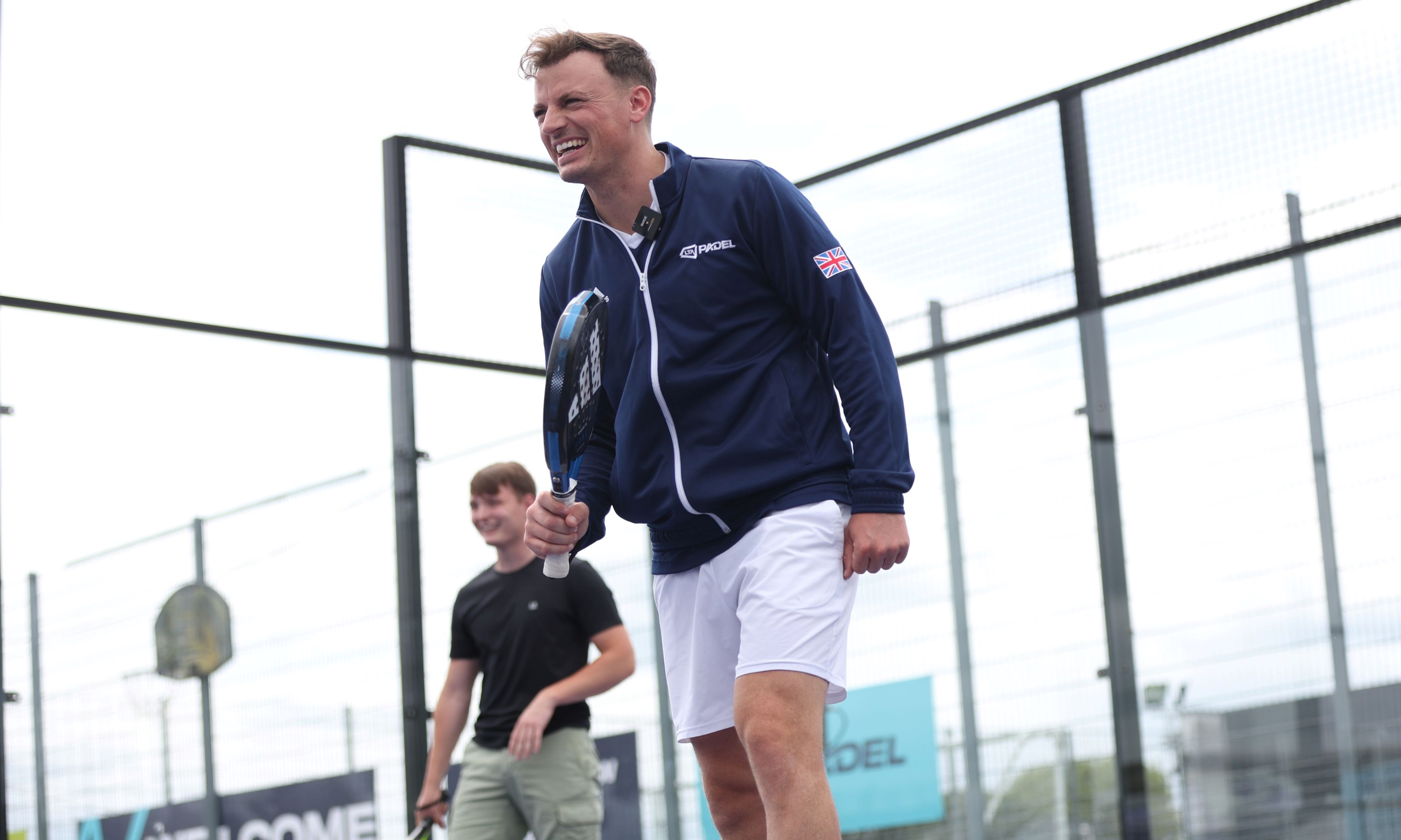 Frankie Langan smiling on court with his partner in the background