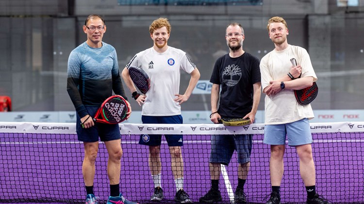 A group of four posing with their padel rackets.