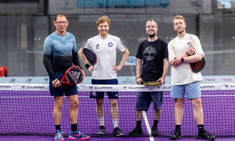 A group of four posing with their padel rackets.
