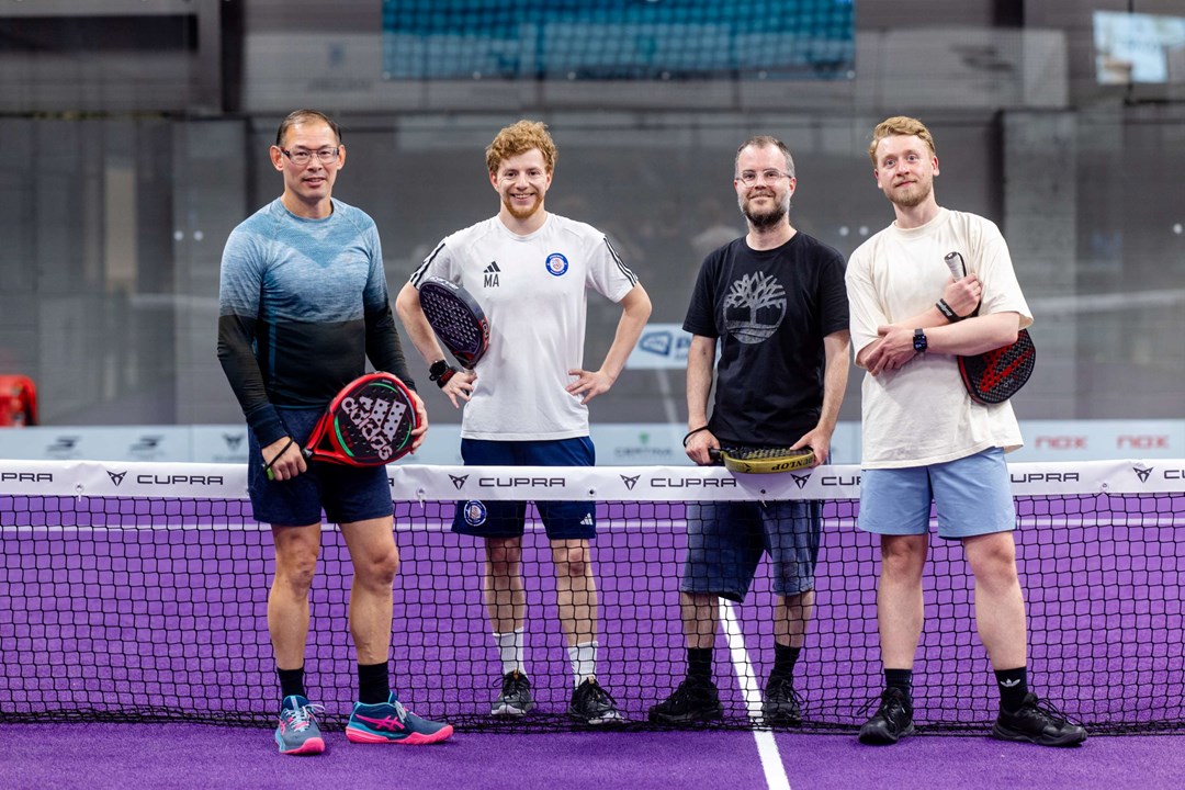 A group of four posing with their padel rackets.
