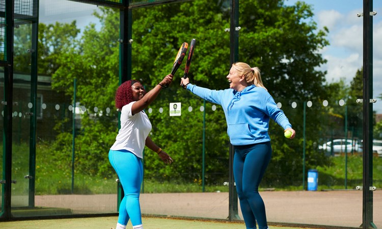 Two players smiling and tapping padel rackets