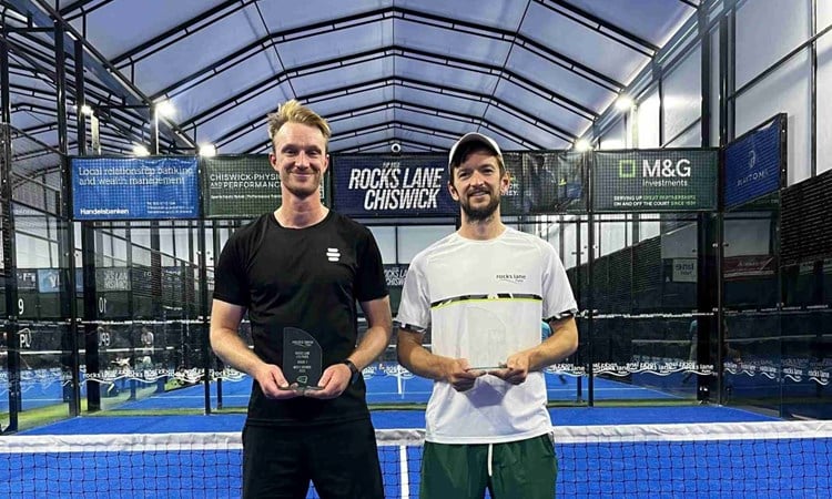 British padel players Nicholas Hatchett and Sam Macneil holding their trophies and smiling on court at the LTA Padel British Tour event at Rocks Lane, Chiswick