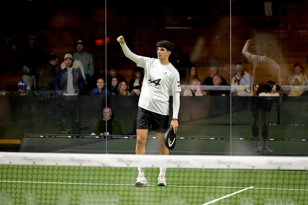 Spanish padel player Arturo Coello holding a padel racket and raising his arm up on a green padel court