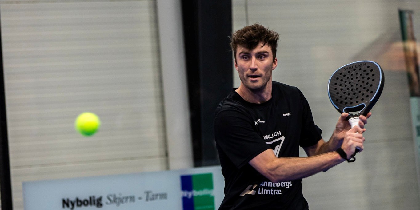 British padel player Alex Loughlan preparing to hit a backhand on court at a padel tournament