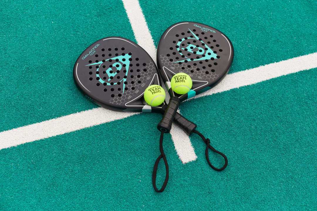 a pair of padel rackets and balls placed on the padel court