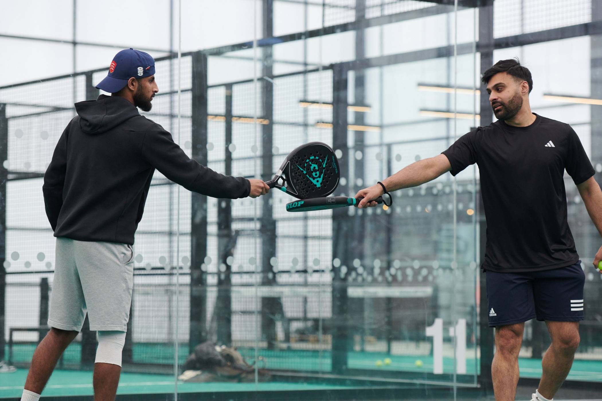 A padel doubles partnership touching rackets in between points