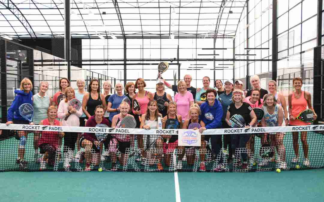The attendees of the 2024 Female Padel Participation Day posing behind a padel net