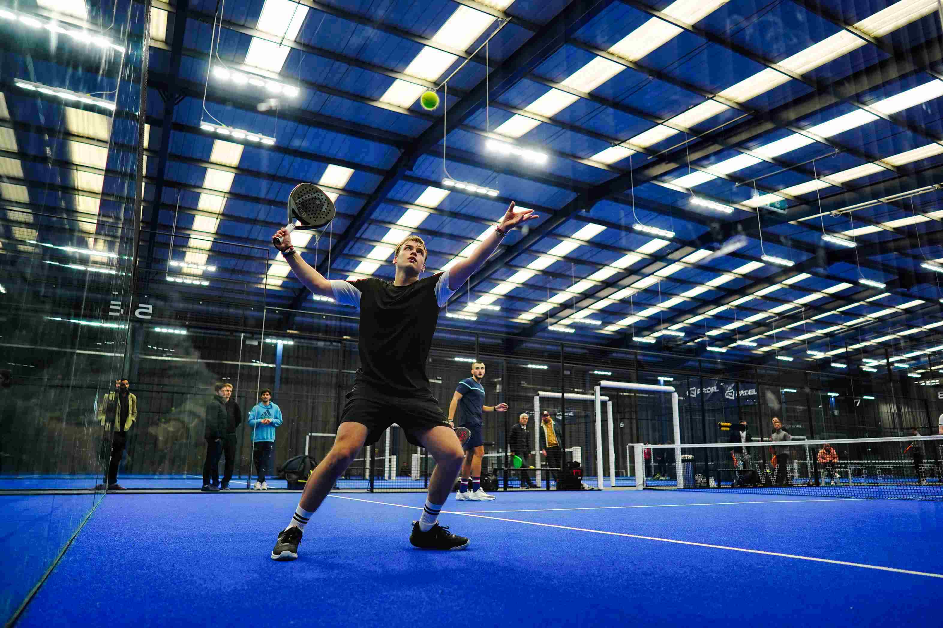 A player hitting the ball off the wall at the LTA Padel British Tour in Derby