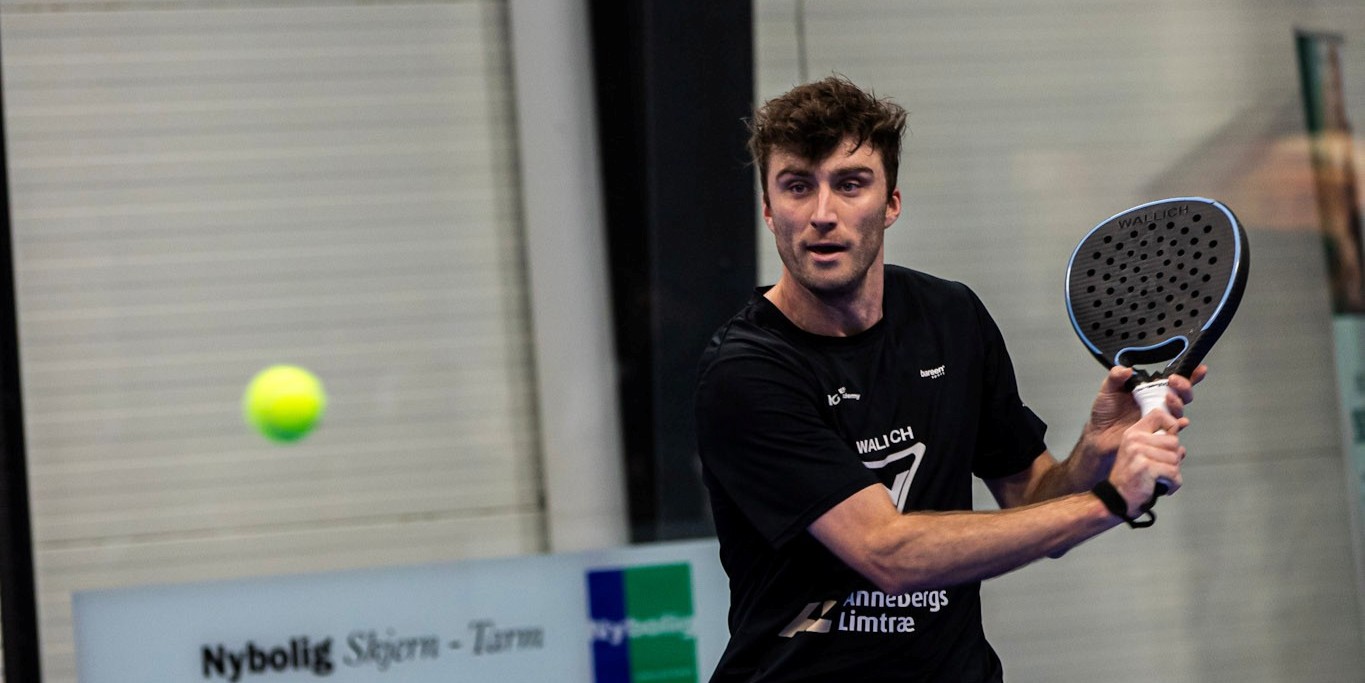 British padel player Alex Loughlan preparing to hit a backhand on court at a padel tournament