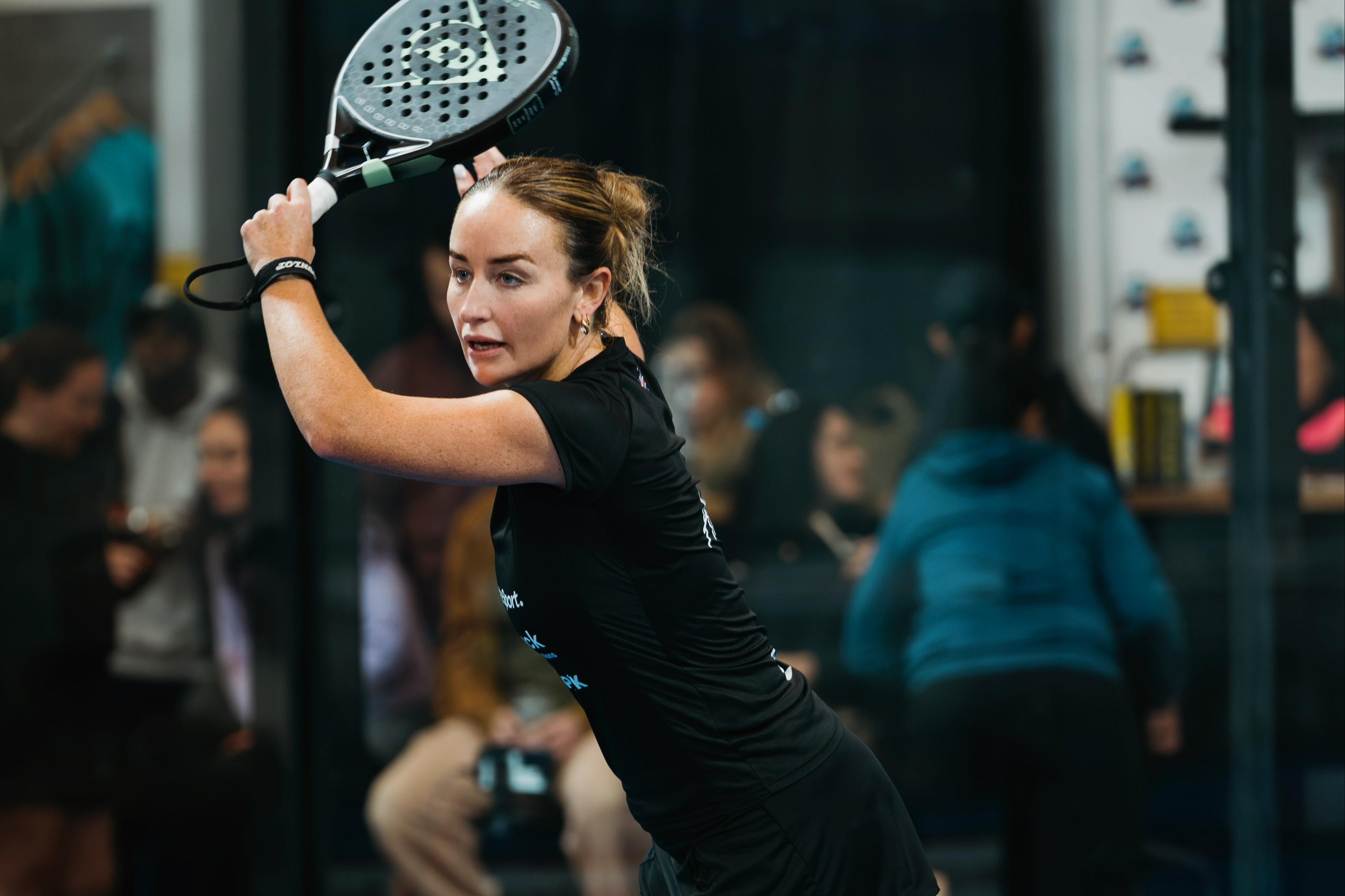 British padel player Aimee Gibson with her racket in the air after hitting a shot