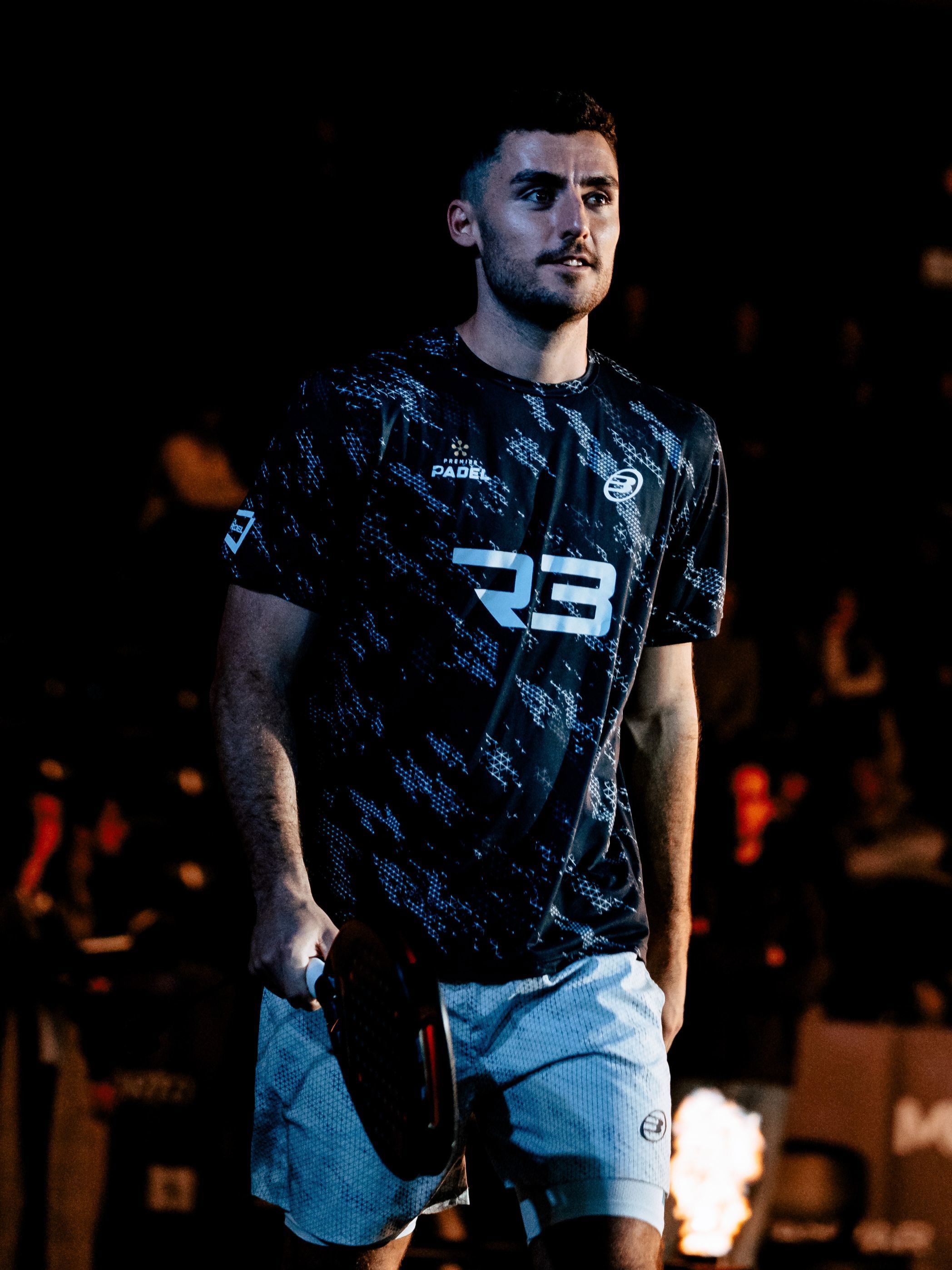 British padel player Christian Medina Murphy walking out onto court smiling and holding a padel racket